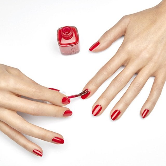 Ein roter, klassischer Nagellack von essie wird auf die Fingernägel aufgetragen.
